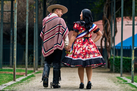 A couple of young Chilean Latin cuecas dancers, walking romantically back to back, gazing affectionately at each other. Chilean Independence Day celebration.