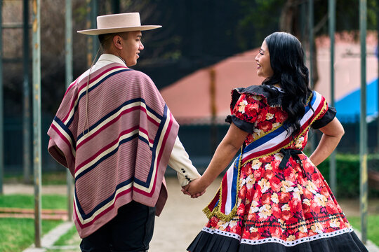 A couple of young Chilean Latin cuecas dancers, walking romantically back to back, gazing affectionately at each other. Chilean Independence Day celebration.