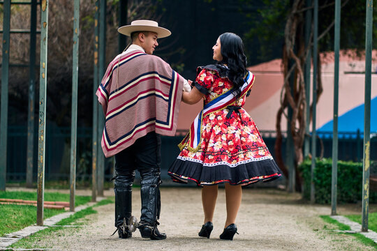 A couple of young Chilean Latin cuecas dancers, walking romantically back to back, gazing affectionately at each other. Chilean Independence Day celebration.