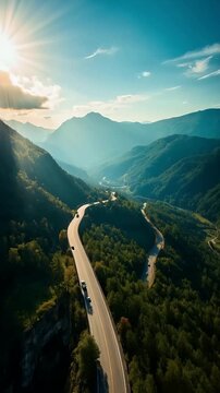 Winding Mountain Road through Forested Valley at Sunset with Cars in Motion &ndash; Aerial View
