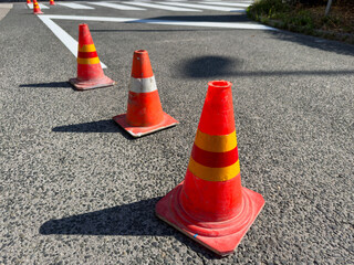 Traffic cones placed on a street near a freshly painted pedestrian crosswalk. Road is temporarily...