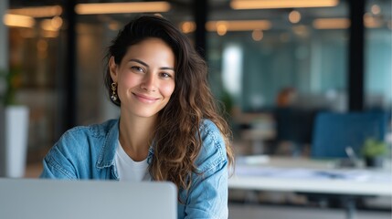 Smiling latin hispanic female marketing manager, professional it specialist working, browsing at laptop computer sitting at desk in modern office. Cheerful young woman employee using pc for business