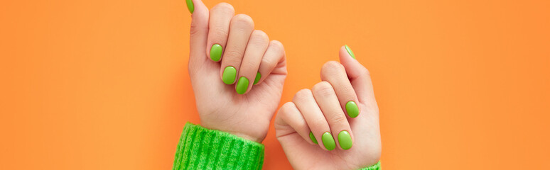 Beautiful womans hands with spring autumn nail design on orange background. Manicure, pedicure beauty salon concept.