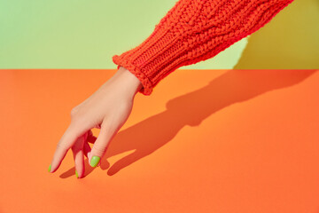 Beautiful womans hand with spring autumn nail design on green and orange background. Manicure,...
