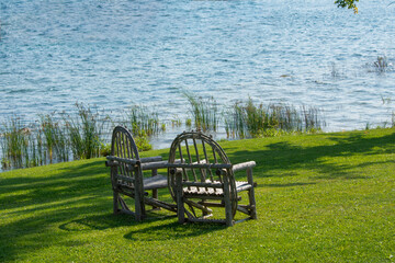 Two old chairs on a green meadow near the lake