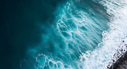 Fototapeta premium Aerial view of blue ocean waves crashing onto a rocky shore