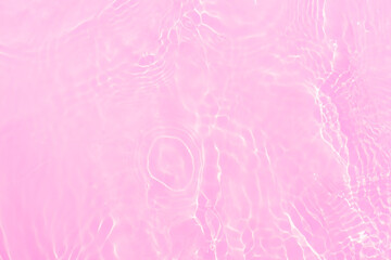 Pink water bubbles on the surface ripples. Defocus blurred transparent pink colored clear calm water surface texture with splash and bubbles. Water waves with shining pattern texture background