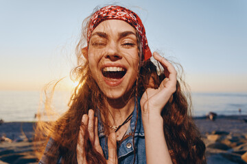 joyful woman laughing with curly hair and red headband outdoors at sunset, natural light, carefree...