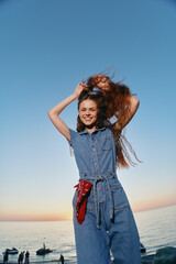 lifestyle woman in modern boho-western denim street style enjoying sunset by sea, smiling with...
