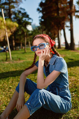 Lifestyle woman in modern boho-western denim street style wearing blue sunglasses and red headscarf...