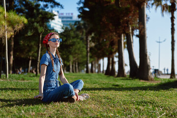 Lifestyle woman in modern boho-western denim street style sitting on grass outdoors, wearing...