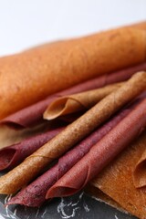 Delicious fruit leather rolls on table, closeup