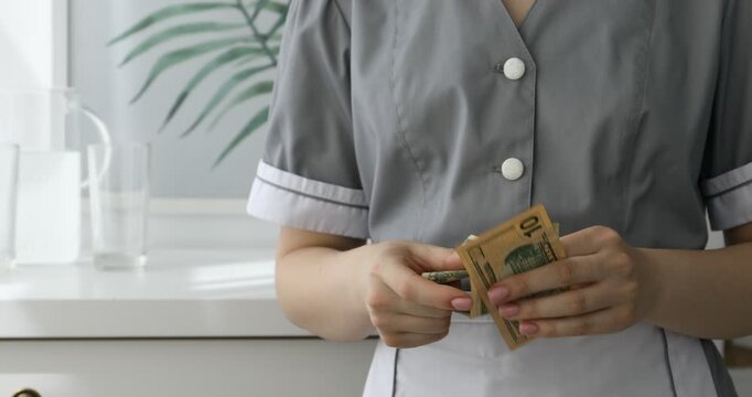 Chambermaid counting tips and hiding them in hotel room, closeup. Gratuity for work