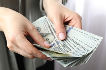 Woman counting dollar banknotes indoors, closeup view