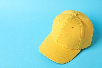Yellow baseball hat on light blue background, above view. Space for text