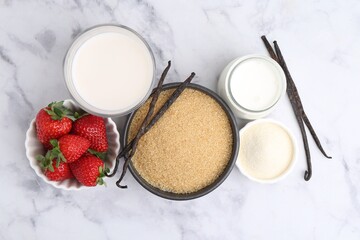 Different ingredients for panna cotta. Milk, sugar, vanilla and strawberries on white marble table, flat lay