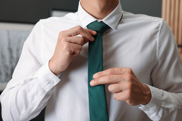Man tying stylish necktie at home, closeup