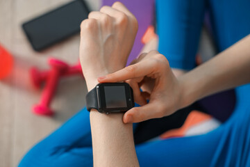 Woman checking fitness tracker during training indoors, closeup