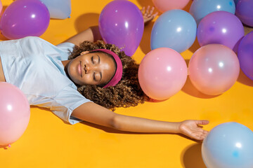 Joyful girl relaxing among colorful balloons