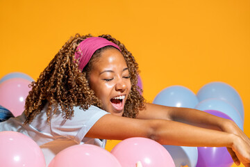 Young woman lying on balloons, enjoying festive atmosphere with closed eyes