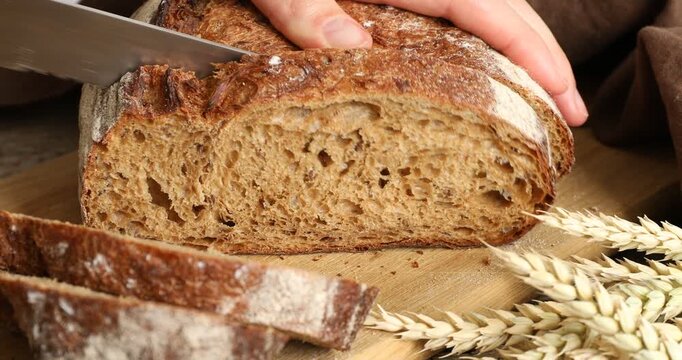 Woman cutting fresh bread at table, closeup