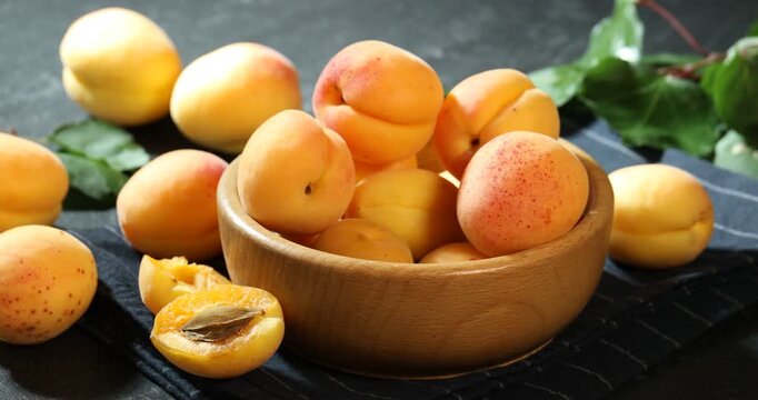 Woman taking fresh ripe apricot from bowl at table, closeup