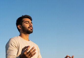 Serene bearded man meditating outdoors against a clear blue sky with copy space