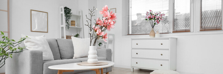 Sofa and coffee table with magnolia flowers in interior of living room