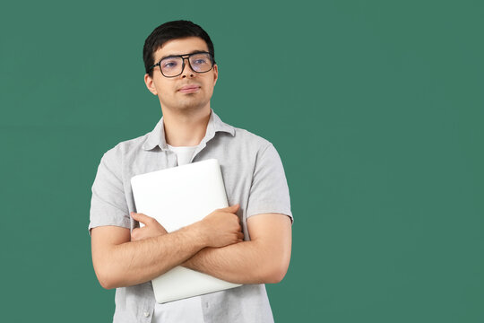 Male programmer with laptop on green background