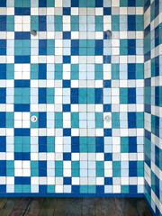 A tiled shower wall features a vibrant blue, white, and turquoise checkered pattern