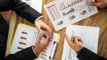 Two business professionals reviewing financial reports and charts together at a desk