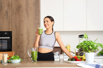 Sporty young woman with healthy smoothie in kitchen
