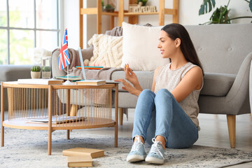 Young woman with laptop learning English language online at home