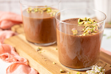Two glasses of chocolate avocado mousse garnished with chopped pistachios