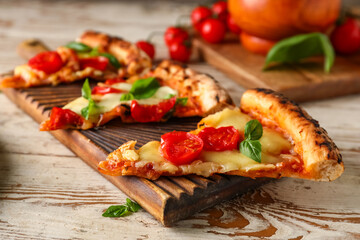 Board with slices of tasty pizza Margarita on light wooden background