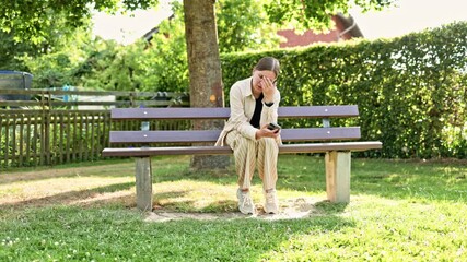 Woman with phone sitting in park on bench and enjoying mobile conversation on sunny morning. Smiling girl talking on mobile phone surrounded by greenery. Happy woman enjoying talking on phone. - Powered by Adobe