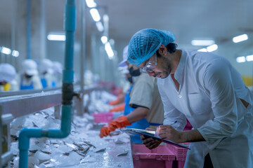 Food processing workers in protective gear, including lab coats, hair covers, and goggles, inspecting fish on ice in a factory setting, emphasizing hygiene, quality control, and safety standards.
