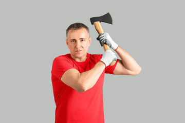 Portrait of adult lumberjack swinging axe on grey background