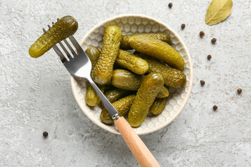 Bowl with tasty pickled cucumbers and peppercorn on grey background