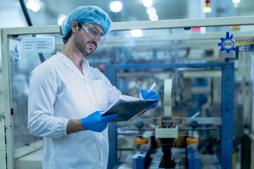 A food processing supervisor wearing protective gear and holding a clipboard, inspecting operations...