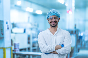 A confident food processing supervisor in protective gear, standing with arms crossed next to machinery in a factory, symbolizing leadership, quality assurance, and operational safety.