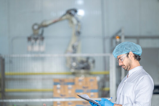 A quality control specialist in a modern factory inspects production processes while recording data on a clipboard. The robotic arm and automation highlight efficiency in manufacturing. - Powered by Adobe