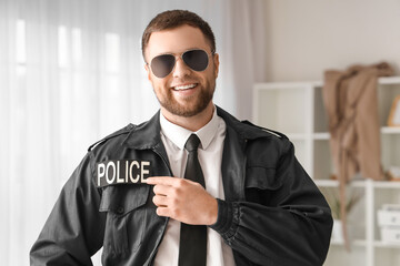 Male police officer pointing at uniform indoors