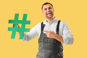 Male gardener pointing at hashtag on yellow background