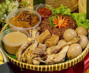 Authentic Indonesian food platter showcasing gudeg, opor ayam, tofu, sambal, and vegetables,...
