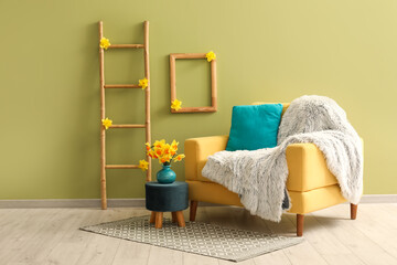 Cozy armchair with plaid, ladder and daffodil flowers in living room