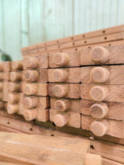 Stack of wooden components with round tenons prepared for joinery inside a woodshop. Close-up with...