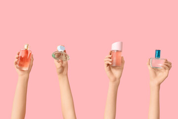 Female hands with different bottles of perfume on pink background