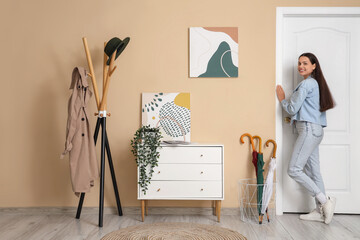 Young woman near door and stylish paintings at home