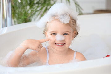 Cute little girl taking bath with foam taking bath in bathroom